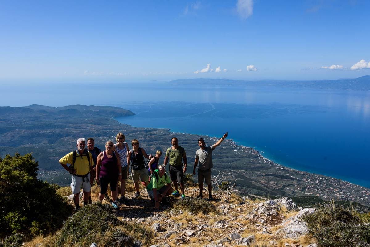 Geführte Wandergruppe auf einem Grat mit Blick auf die Stadt Kalamata und den blauen Messenischen Golf