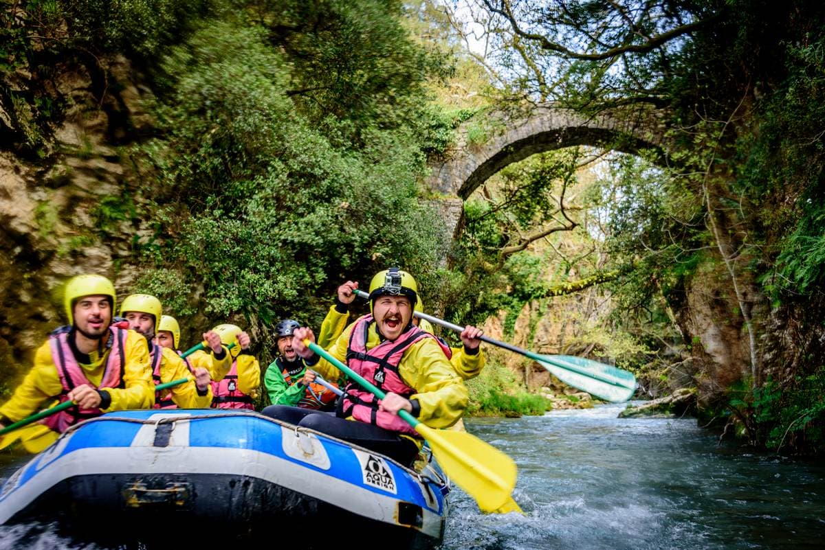 Eine geführte Gruppe paddelt während einer unserer professionellen Rafting-Touren in Griechenland unter einer antiken Steinbrücke hindurch.