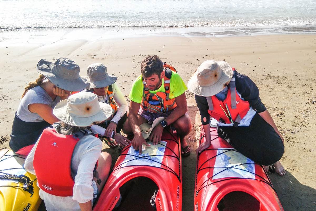 Gids die een kaart laat zien aan reizigers op een zandstrand