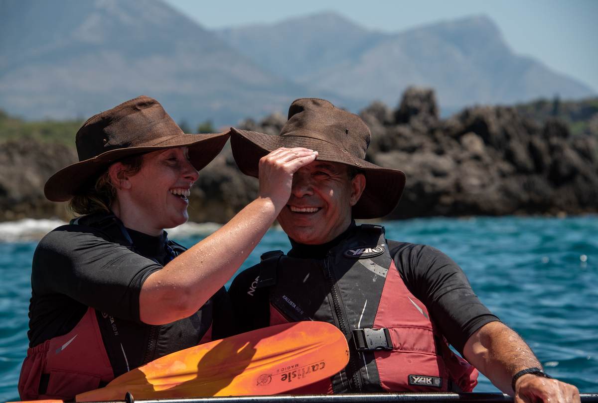 Stel met zonnehoeden die lachen en genieten van een zonnige dag op het water