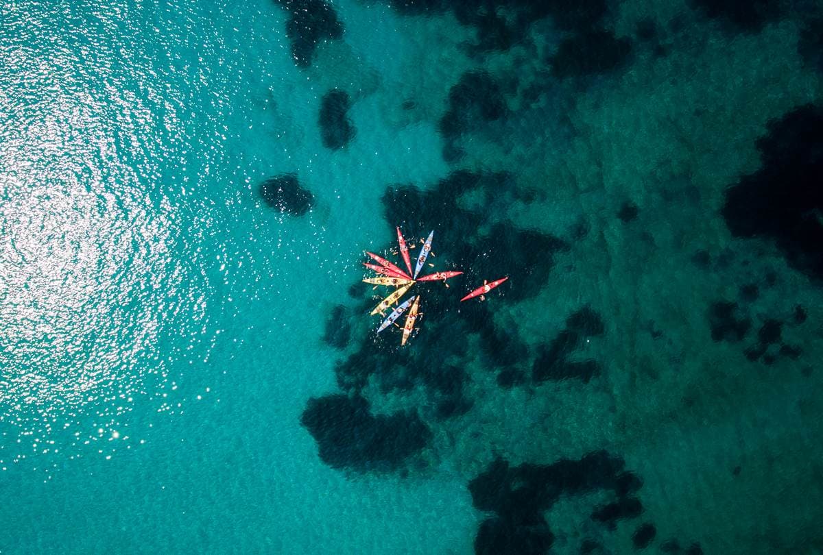 Luchtfoto met een drone van kajaks verzameld in een stervorm boven een helder rif