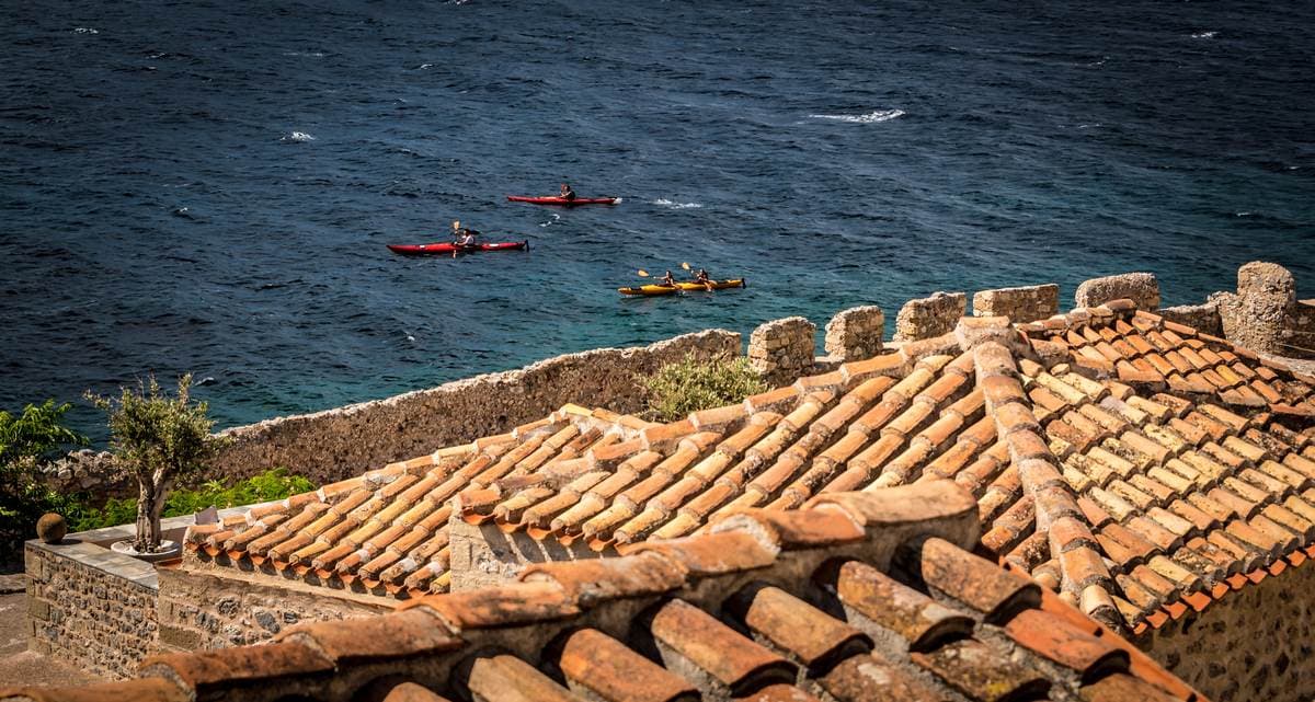 Blick auf die zerklüfteten Klippen und Dächer der Stadt während einer Seekajak-Tour in Monemvasia