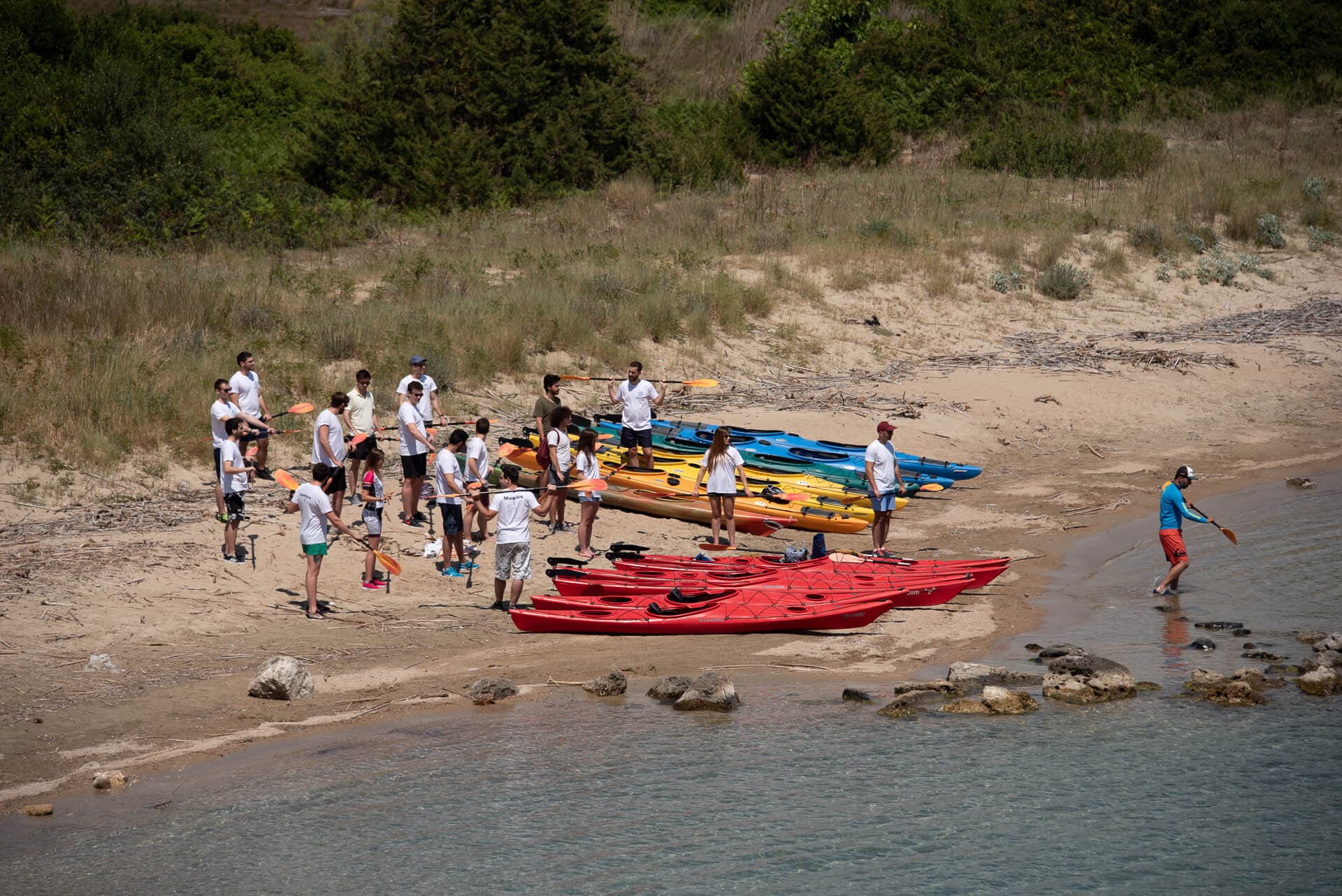 Students preparing for a sea kayaking session on a sandy beach with instructors.