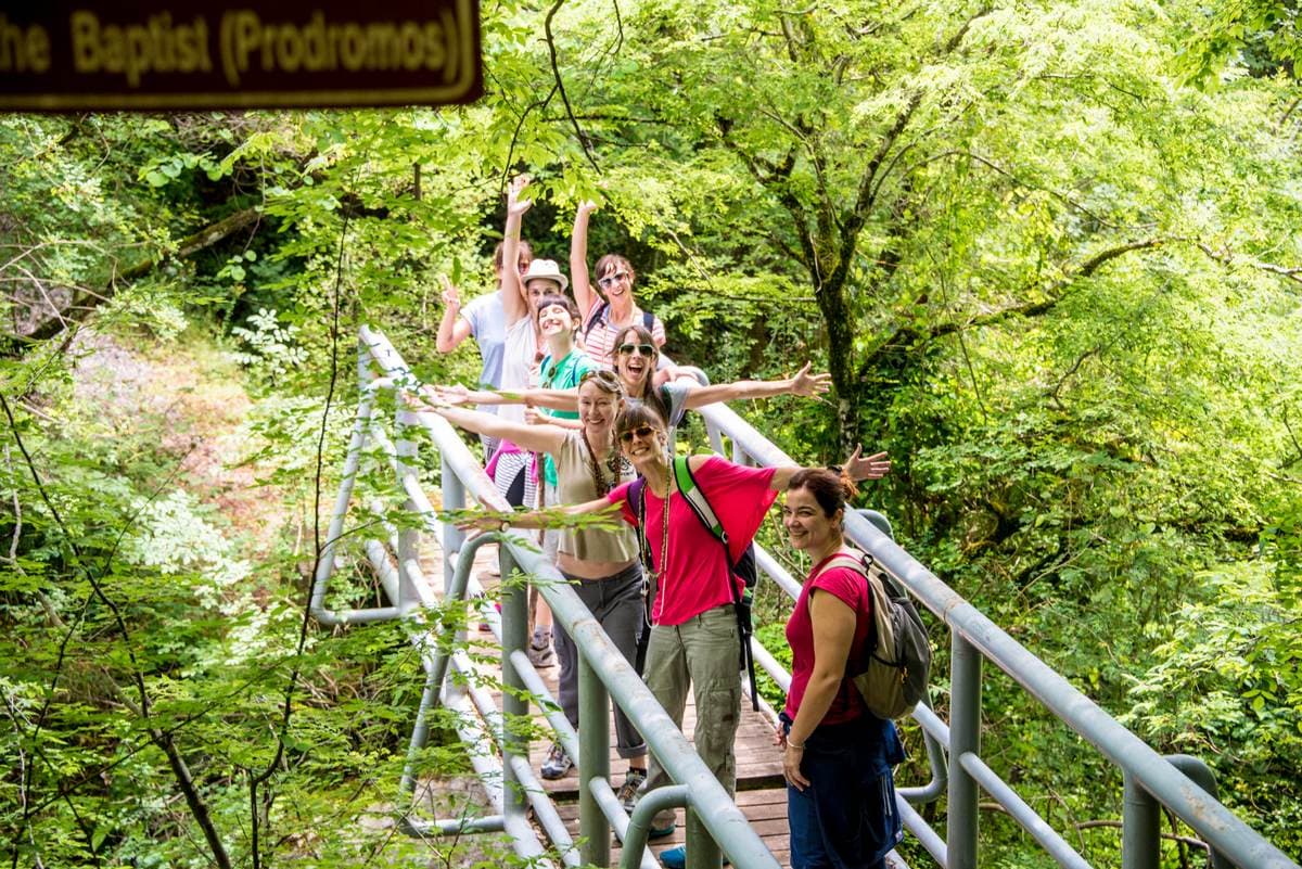 Geführte Wandergruppe überquert eine Steinbrücke über den rauschenden Lousios-Fluss im Menalon-Gebirge