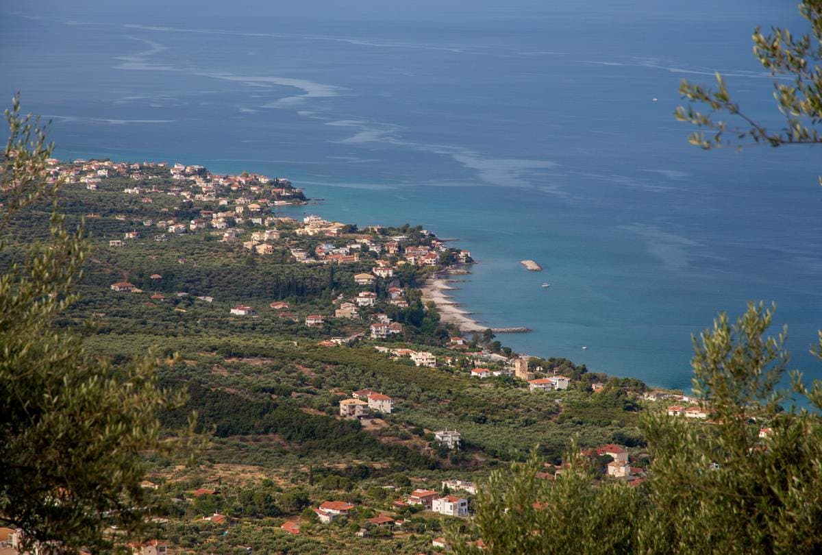 Elevated view over olive groves to a coastal village and turquoise Messinian Gulf above Kalamata