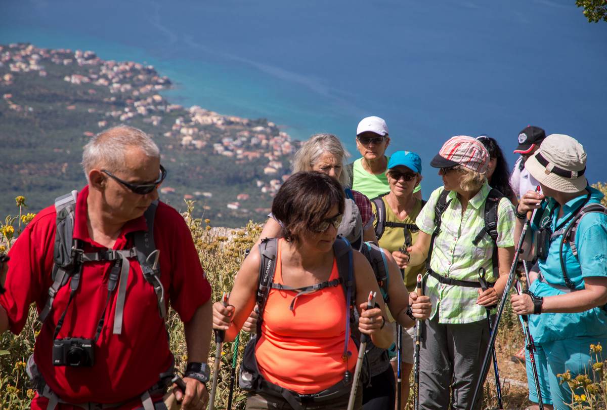 Group of hikers pause on a ridge high above the Kalamata coastline and the deep blue Messinian Gulf
