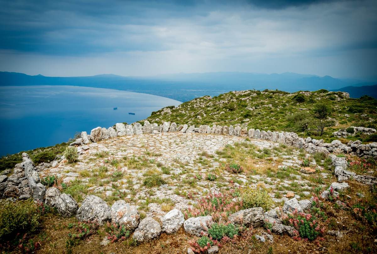 Circular ruined stone wall on a grassy clifftop above the blue Messinian Gulf near Kalamata
