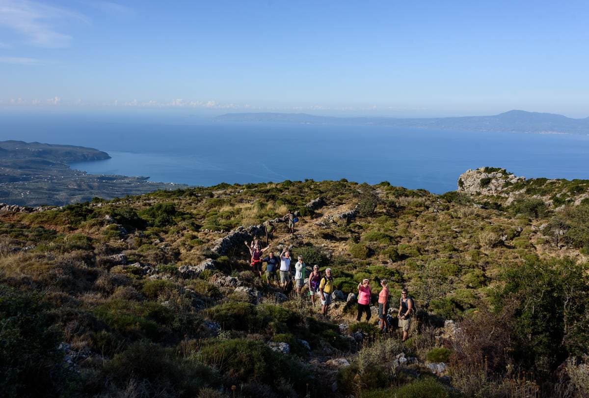 Group of hikers on a scrubby mountain ridge high above the blue Messinian Gulf near Kalamata