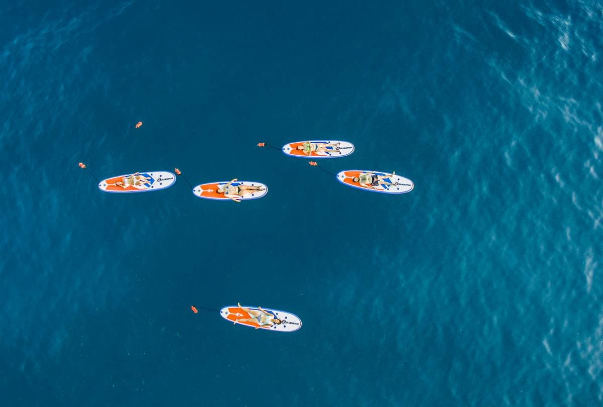 Luftaufnahme von Teilnehmern einer geführten SUP- und Schnorcheltour, die auf Paddleboards im Messenischen Golf, Kalamata, entspannen