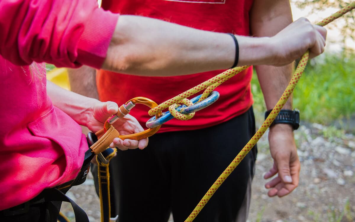 Close-up of hands clipping a carabiner and rope onto a harness before canyoning at Polylimnio