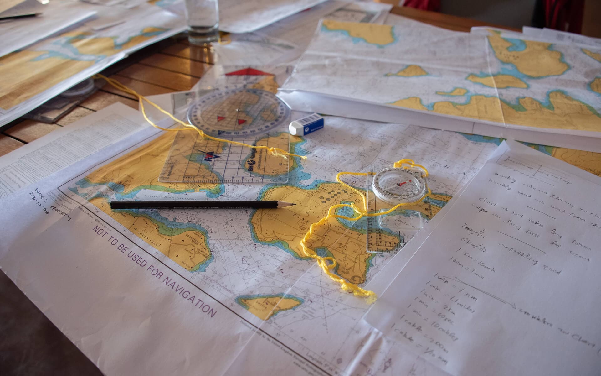 Close-up of nautical navigation charts and a compass used for trip planning.
