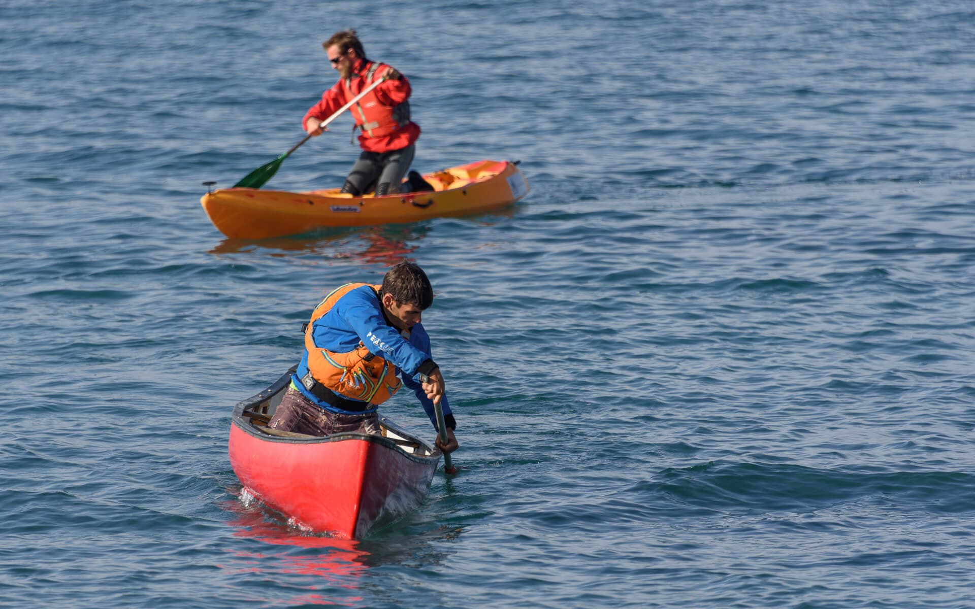 Two people practicing open canoe paddling skills on the open sea.
