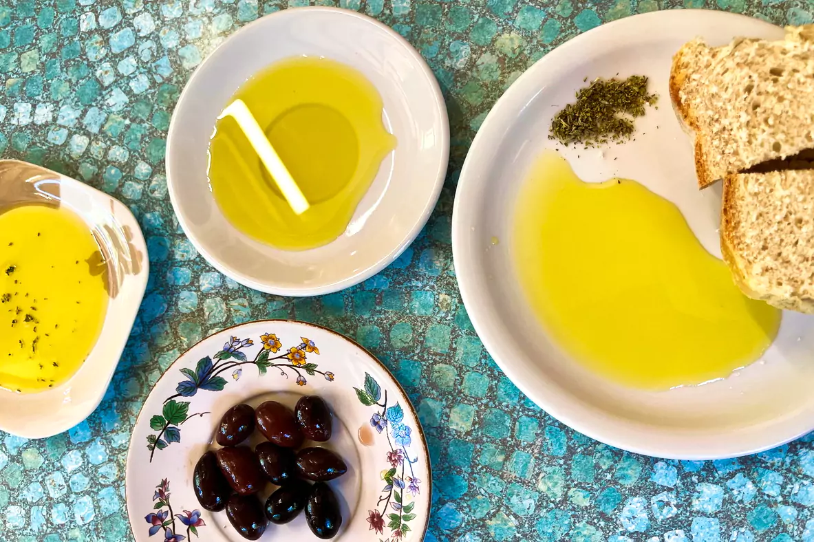 A Mediterranean spread of olive oil, black olives, and bread on rustic plates, celebrating the flavors of Messinia.