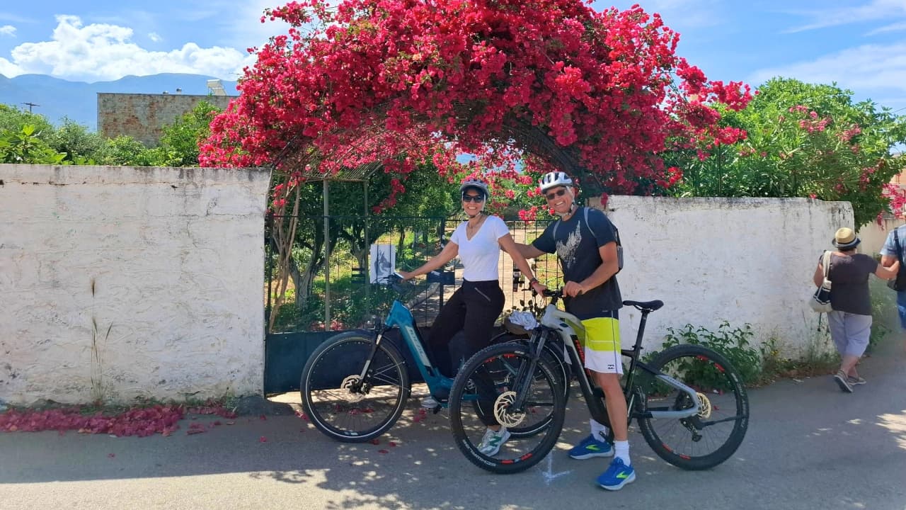 Paar mit Fahrrädern unter einem Bougainvillea-Bogen