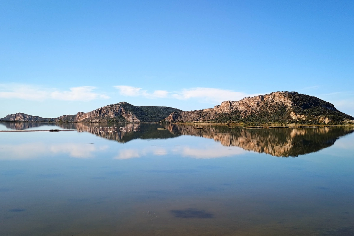 Explore Messinia A calm afternoon in Gialova lagoon with golden hour colors reflections and flamingos.