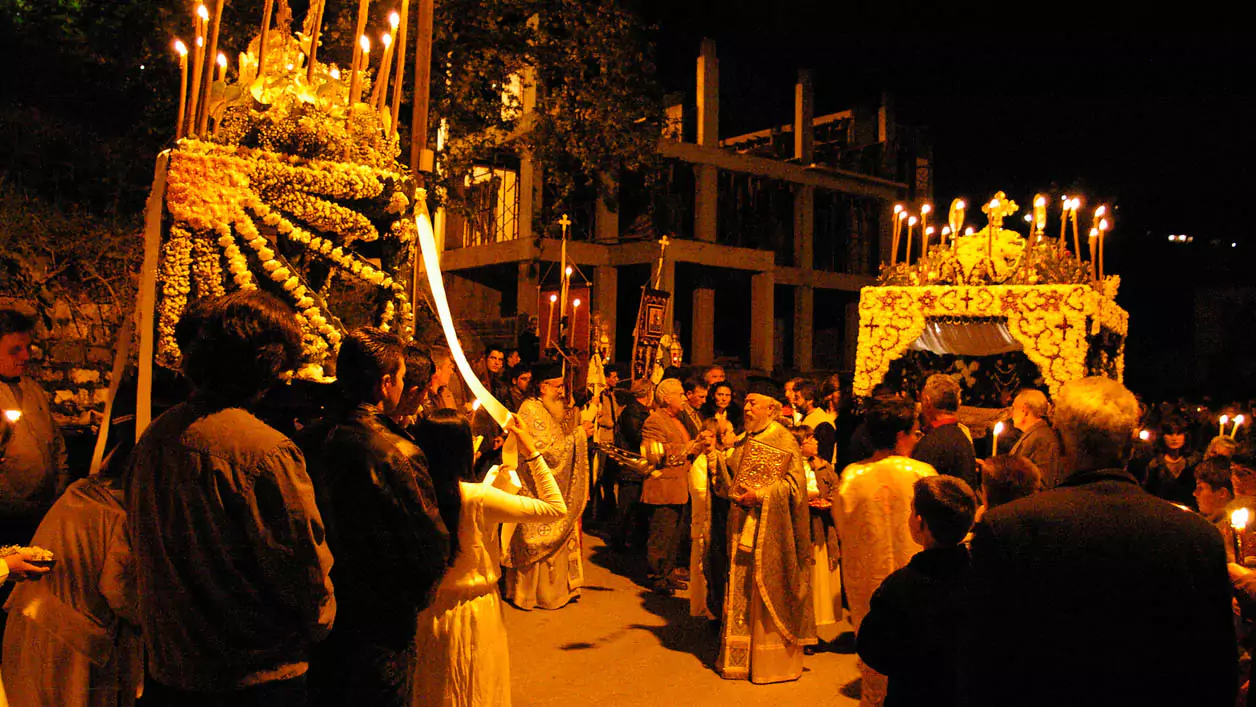 Explore Messinia-Two flower-adorned epitaphs meet in a bustling Peloponnesian square during a Good Friday procession, surrounded by a large crowd of solemn worshippers.