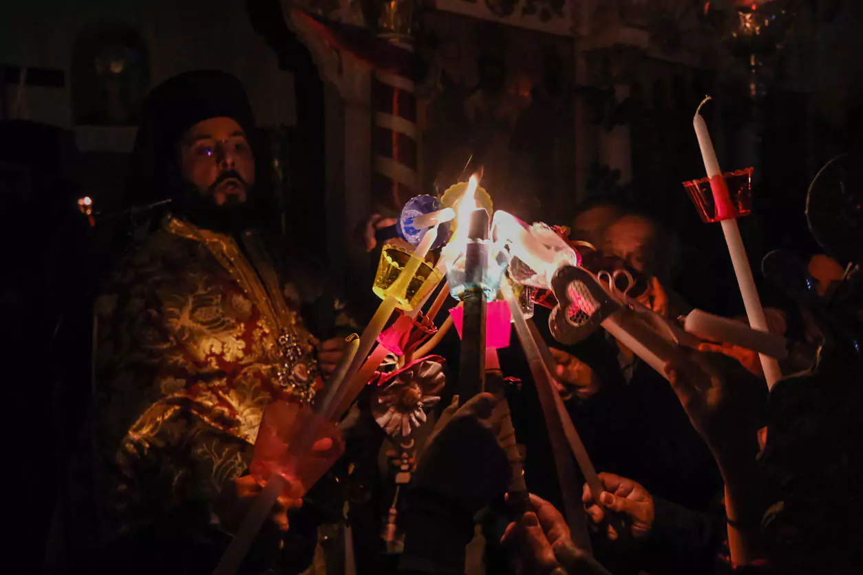 Explore Messinia-A priest surrounded by worshippers holding lit candles as they eagerly await the Holy Light during the Midnight Resurrection service.