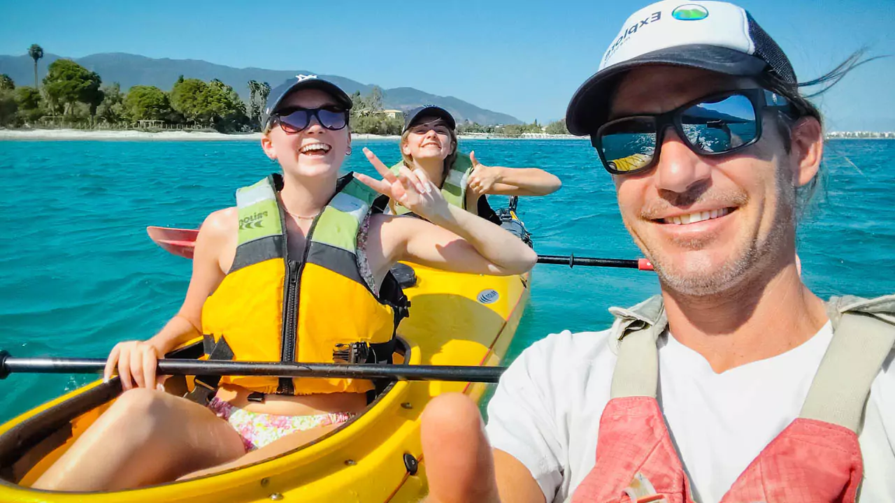 Explore Messinia-Young teenagers with paddles, guided by an adult, exploring a peaceful bay in Messinia, Greece, emphasizing kid-friendly kayaking adventures.