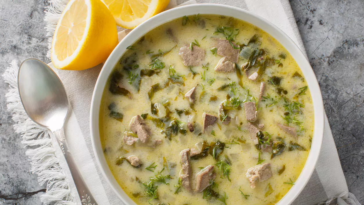 Explore Messinia-A close view of a warm bowl of magiritsa soup garnished with fresh lemons, a traditional Easter dish served after the Midnight Resurrection.