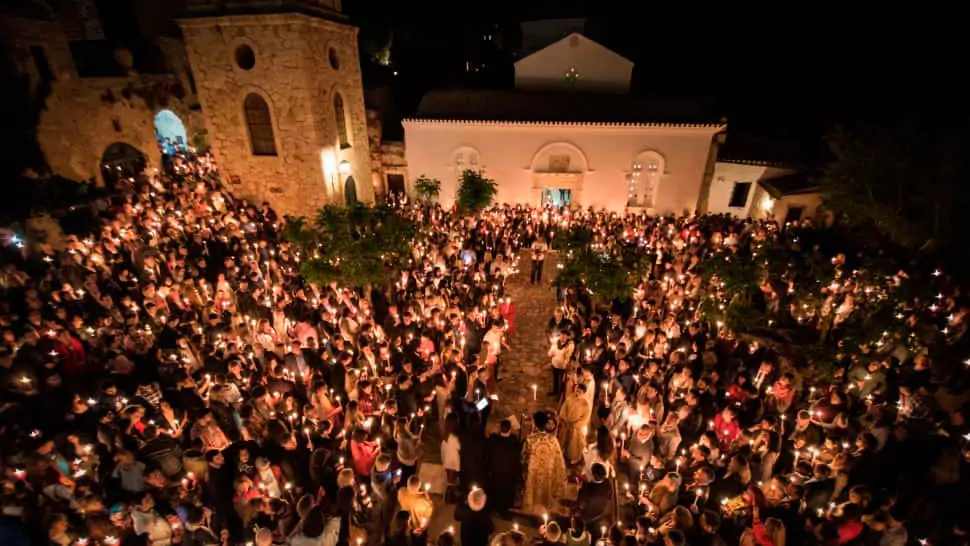 Explore Messinia-A lively square in Monemvasia filled with worshippers holding lit candles during the Midnight Resurrection celebration under a clear starlit sky.