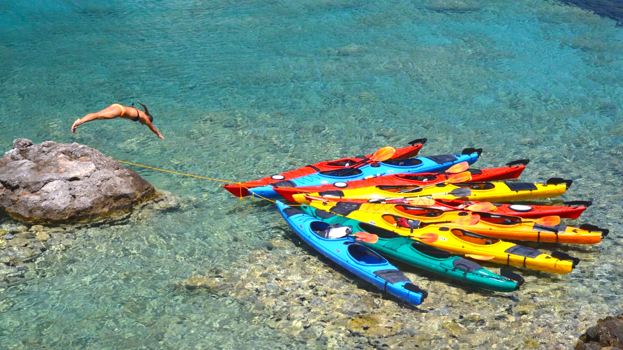 Turquoise waters near Kardamyli. Sea kayaks in turquoise waters near Kardamyli with a person mid-dive from a rock.